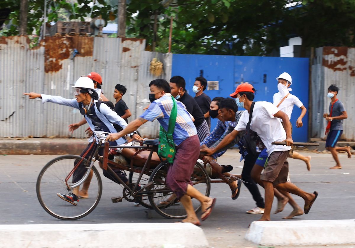 People transport a person who was shot during a security force crackdown on anti-coup protesters in Myanmar
