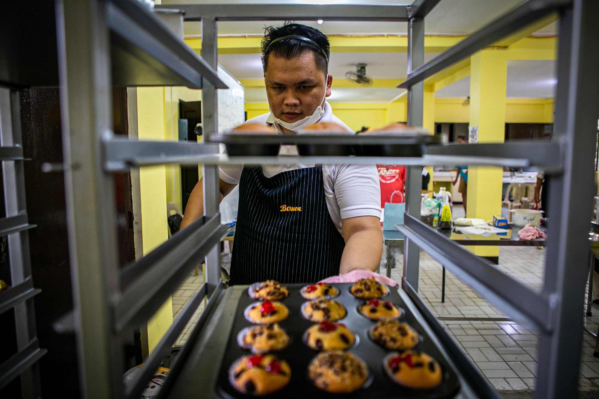 A participant of the training course places newly-baked cupcakes on the tray stand.