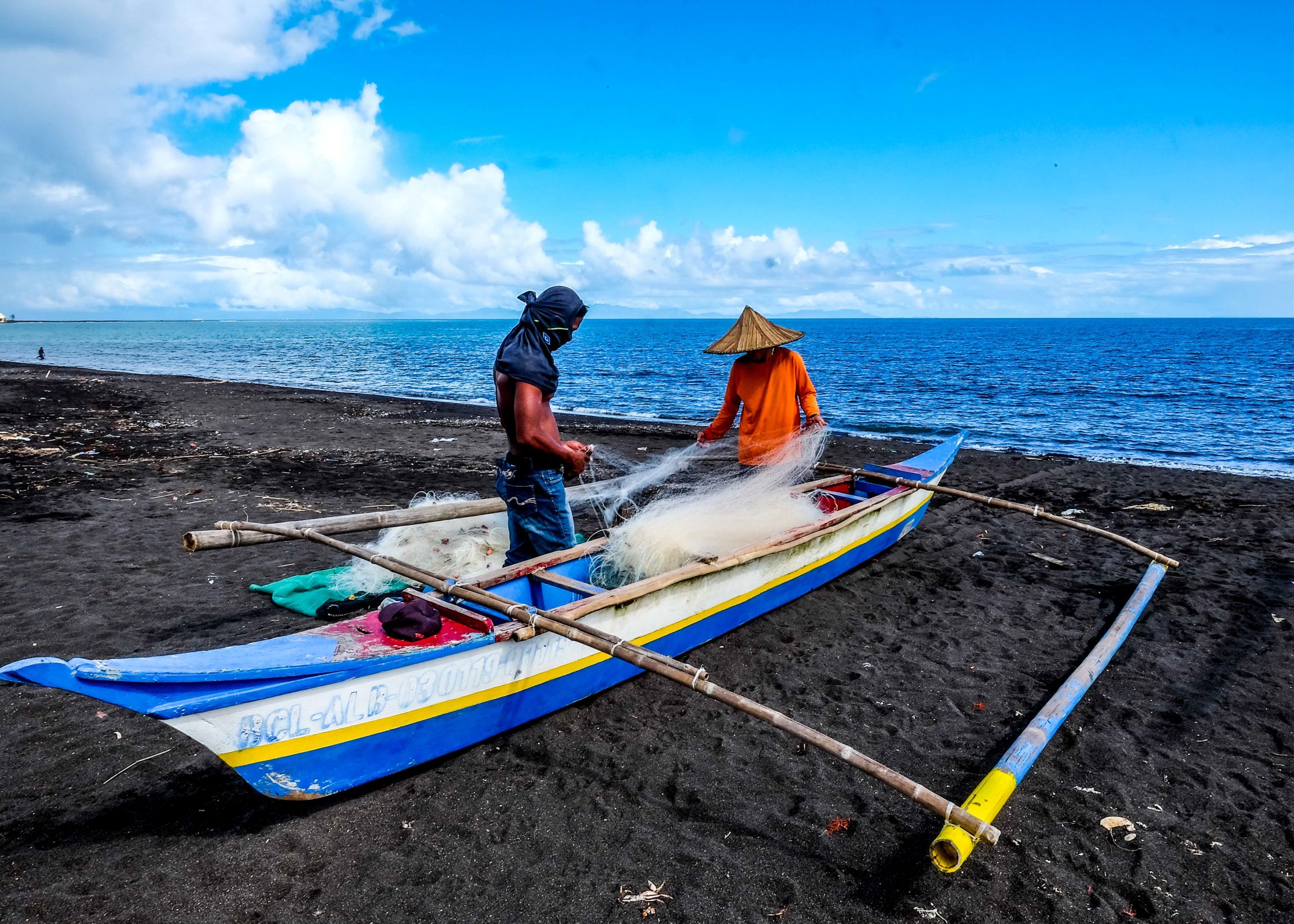 Fishermen fix their nets on the shore of the village of Baybay