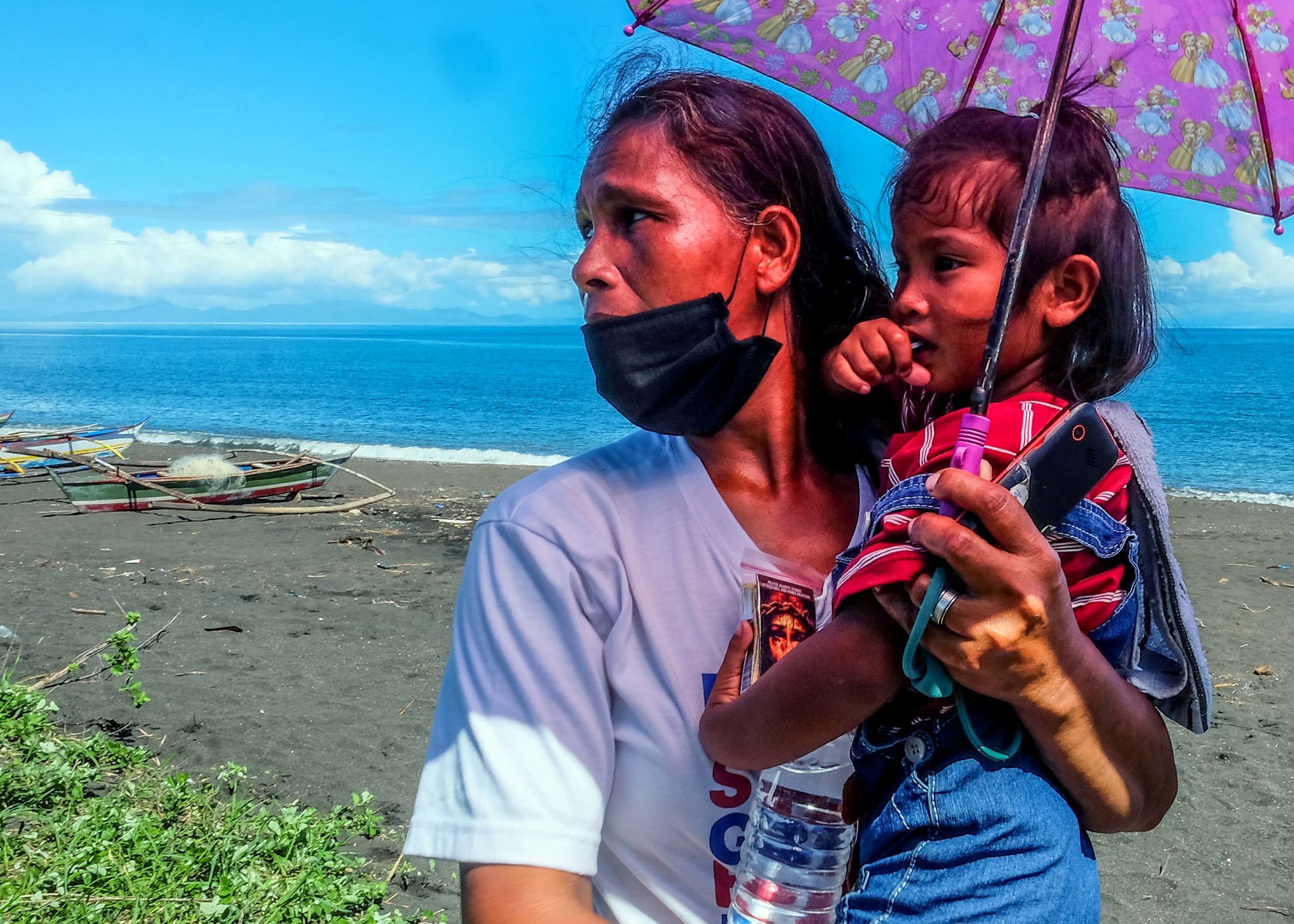 Annalisa Capa, 44, carries her three-year-old daughter on the shore of Baybay village 
