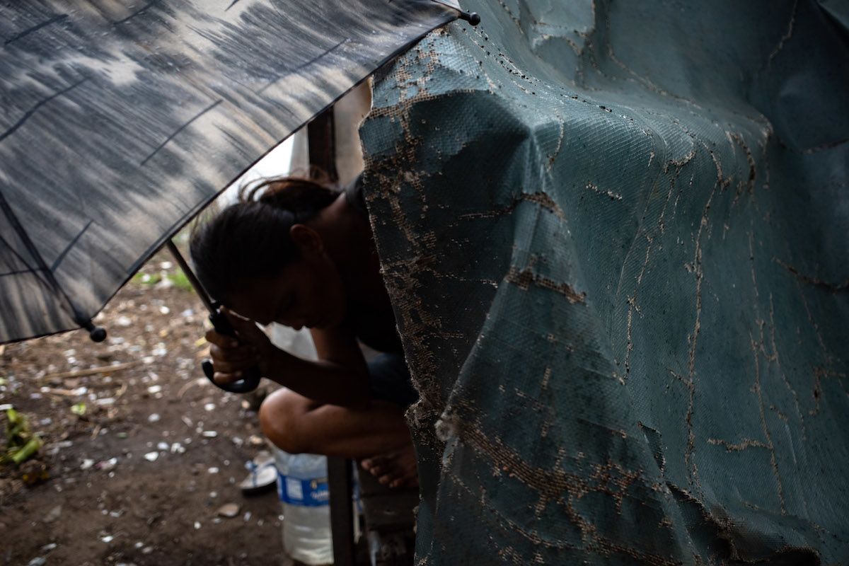 Amy uses an umbrella to shelter herself from the rain.   
