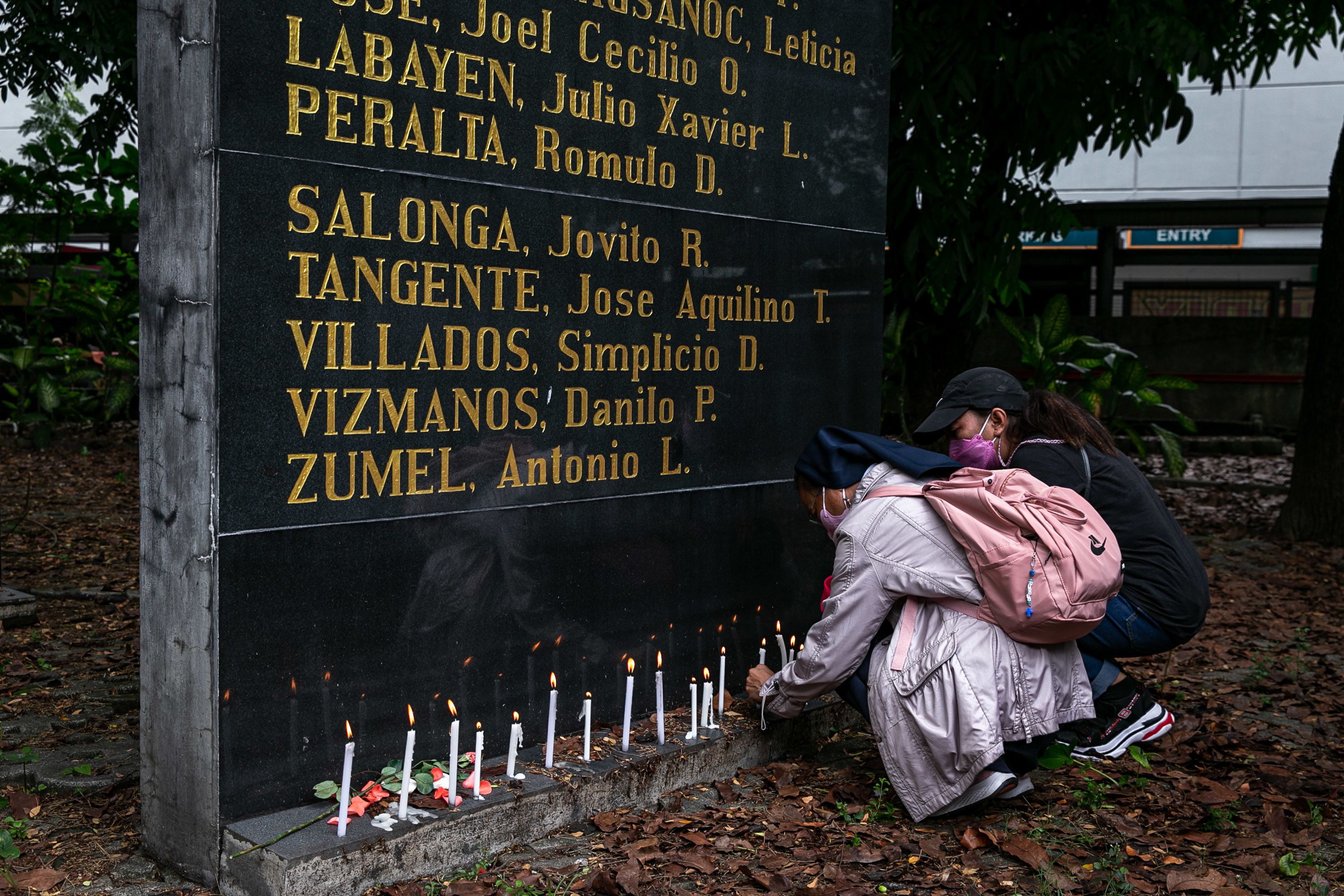 A nun placing a candle at the Bantayog ng mga Bayani