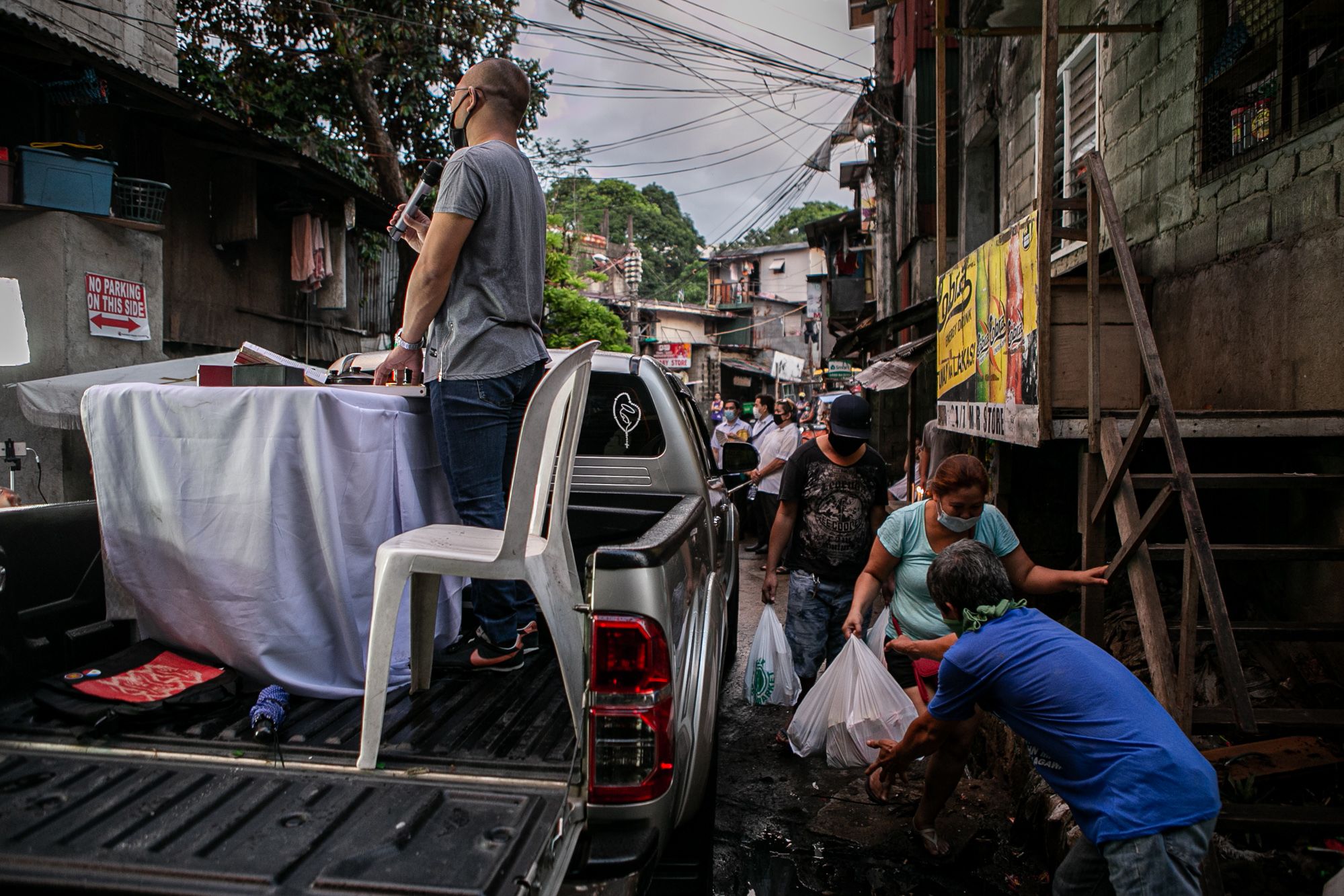 The priest instructs the faithful to remain in front of their houses and observe proper distancing and health protocols.