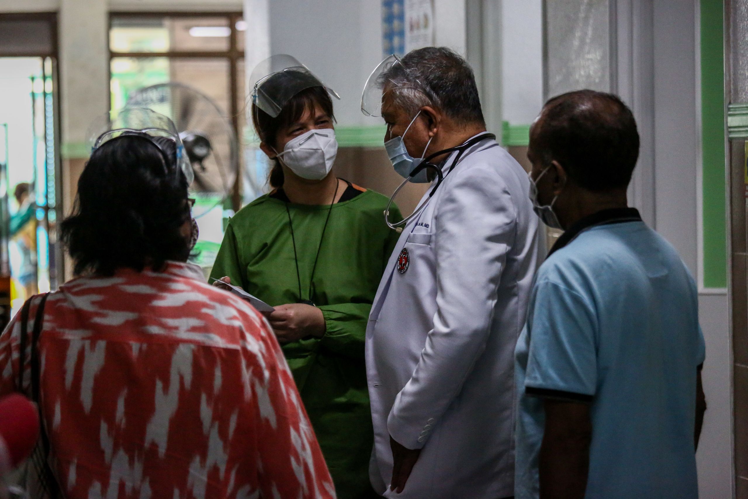 Father Jaime Roa speaks with his patients and medical staff
