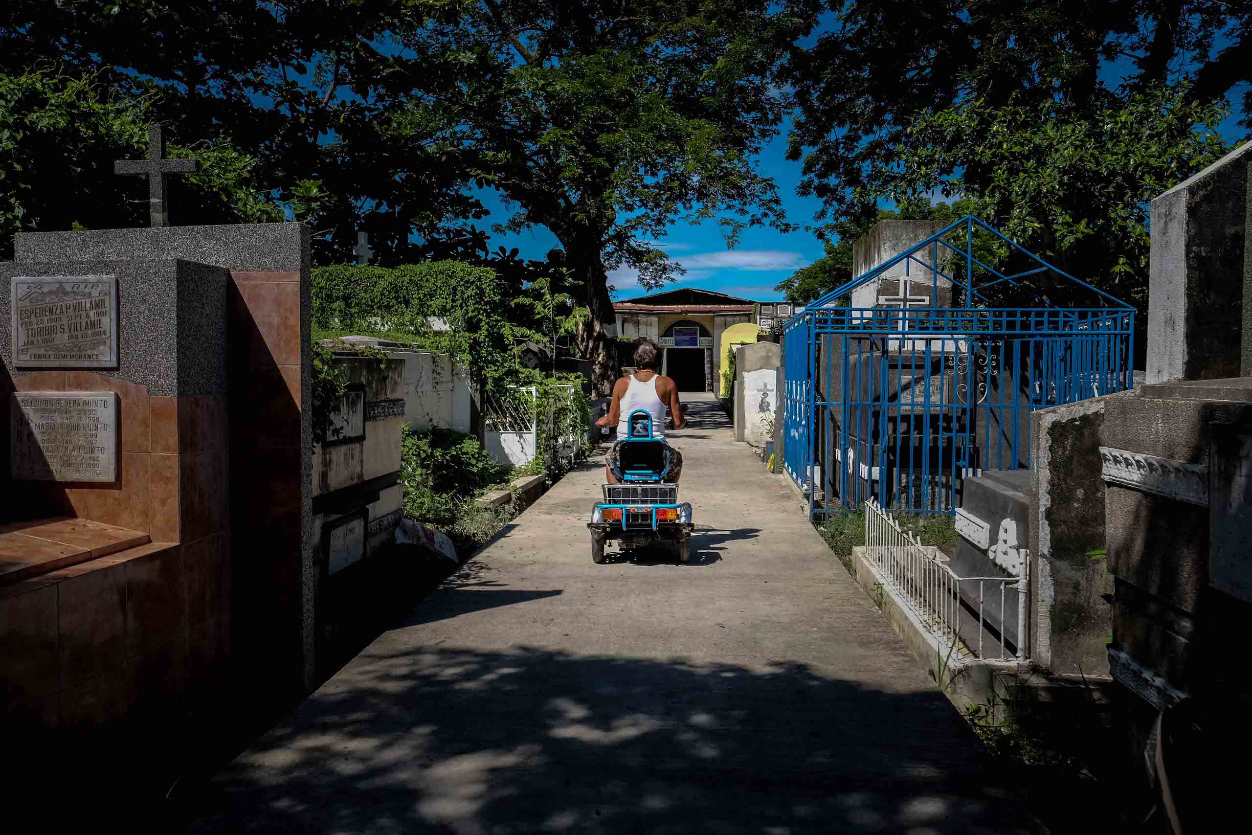 Romulo Soriano, cemetery caretaker, rides his scooter