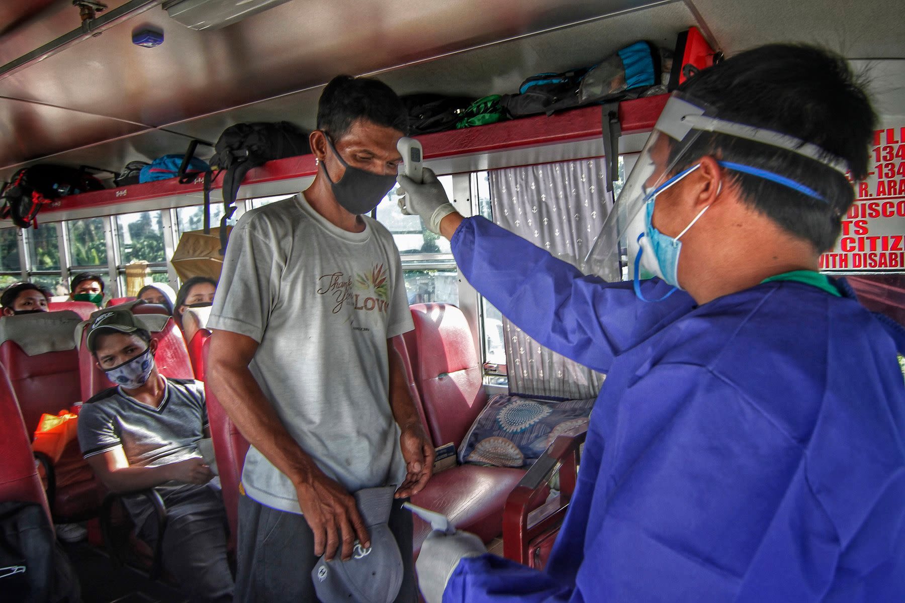 A health worker checks on the temperature of passengers before they were allowed to leave the bus upon arrival in Albay province.