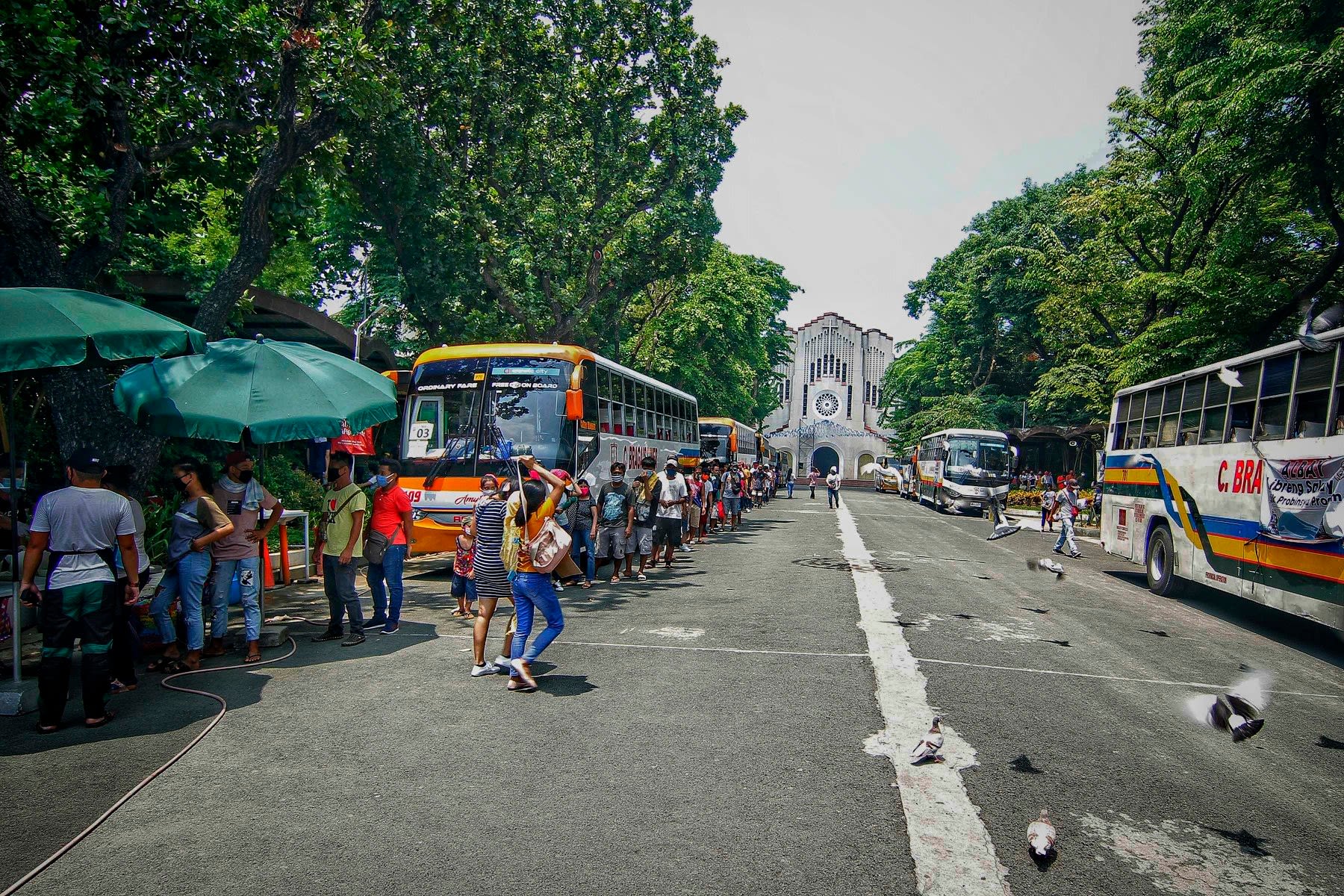 About 600 workers who lost their jobs in the Philippine capital line up to board buses that would bring them home to the province of Albay on June 5. (Photo by Vincent Go)