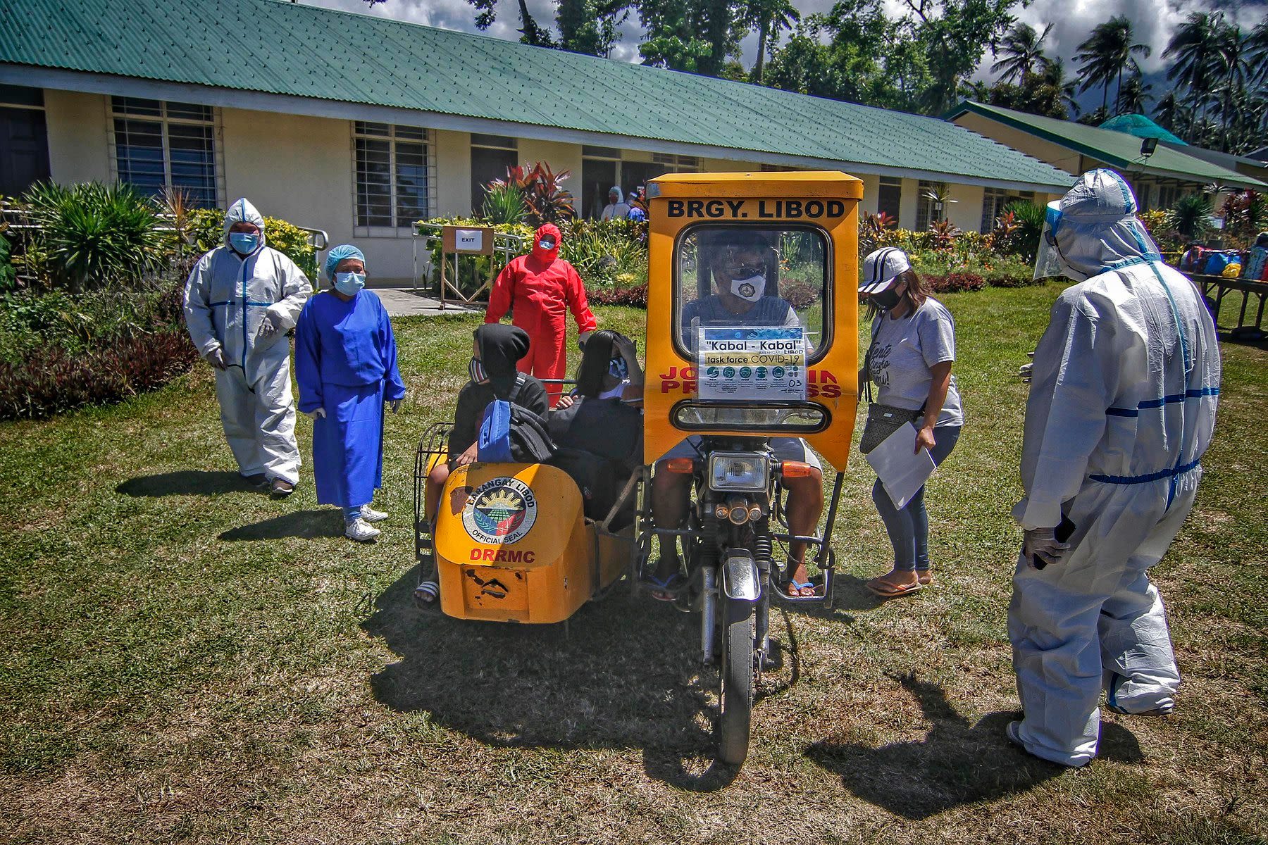 Village officials in protective gear welcome the arriving workers back to the province.