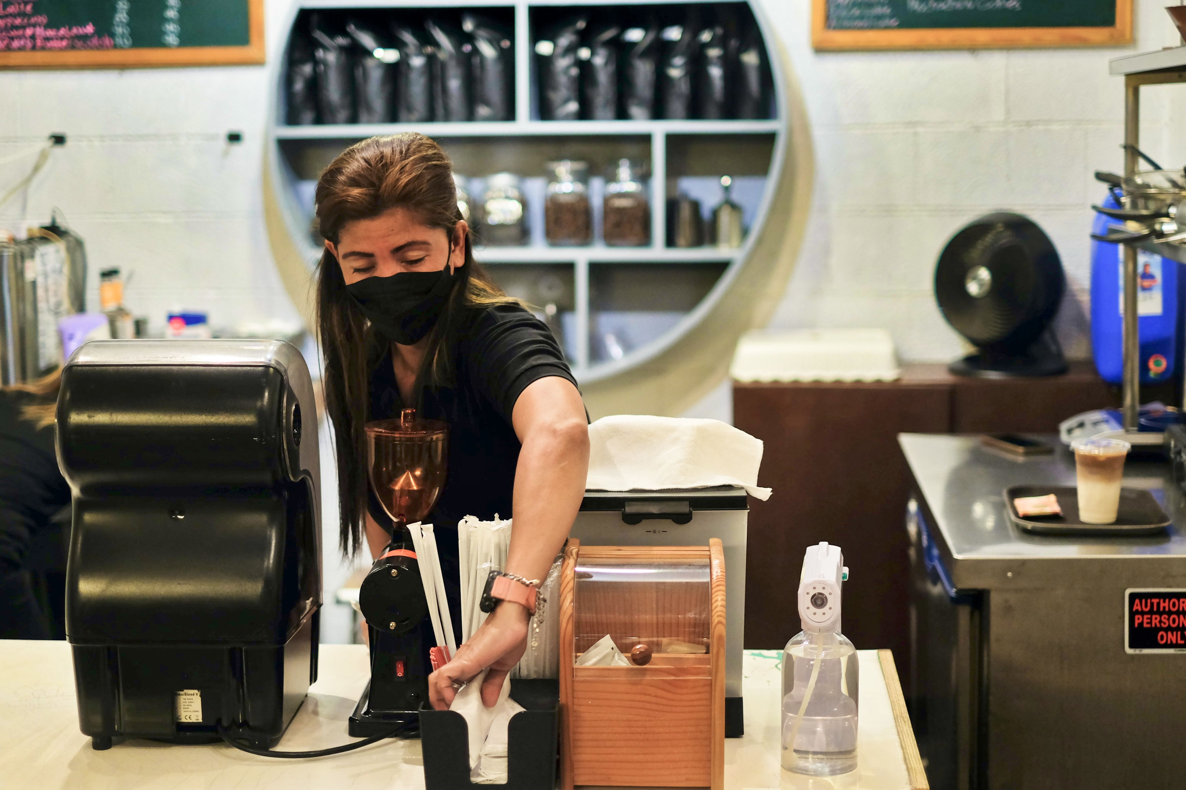 A woman preparing coffee behind the counter in a coffee shop
