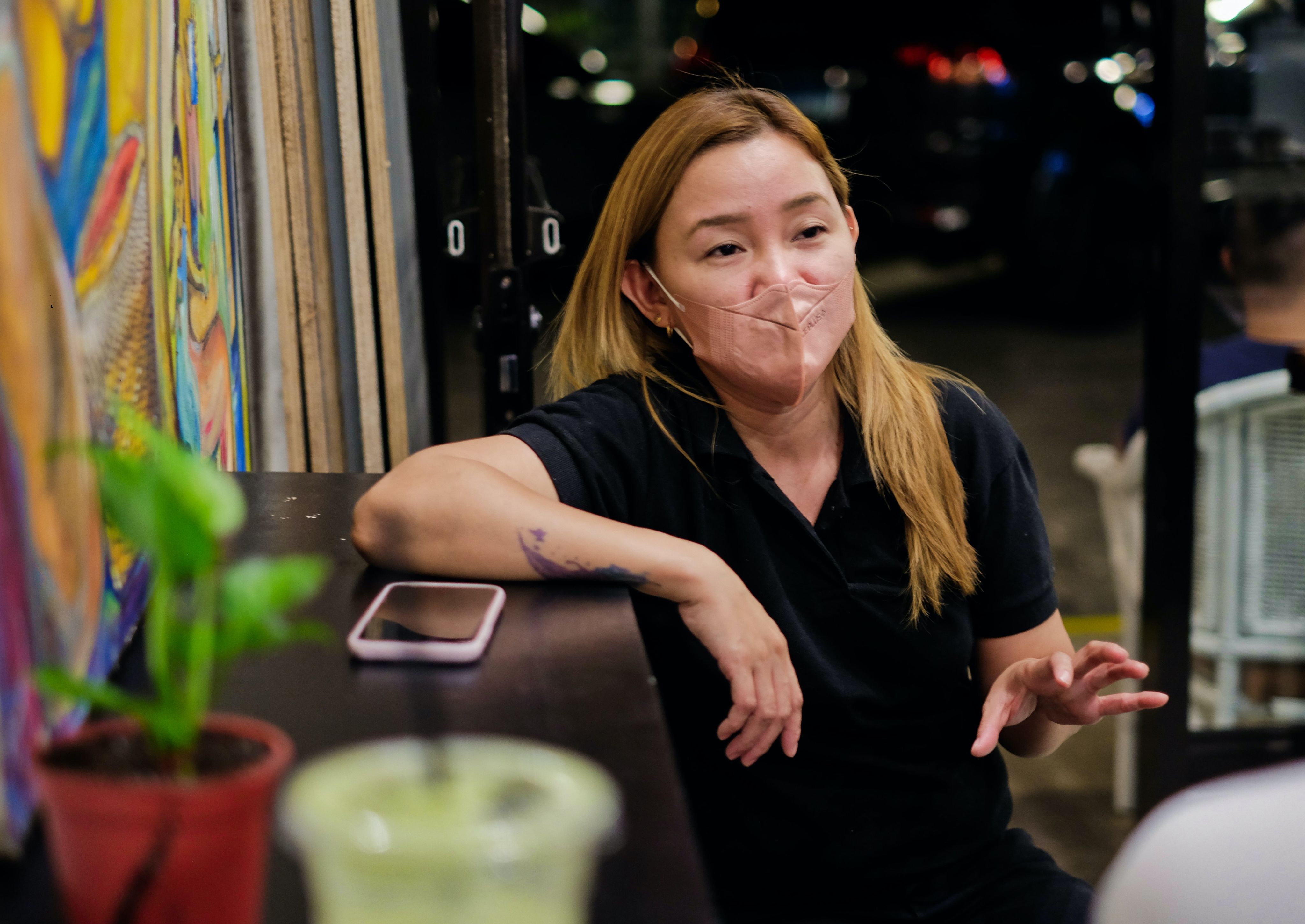 A woman talking while leaning on a side counter at a coffee shop