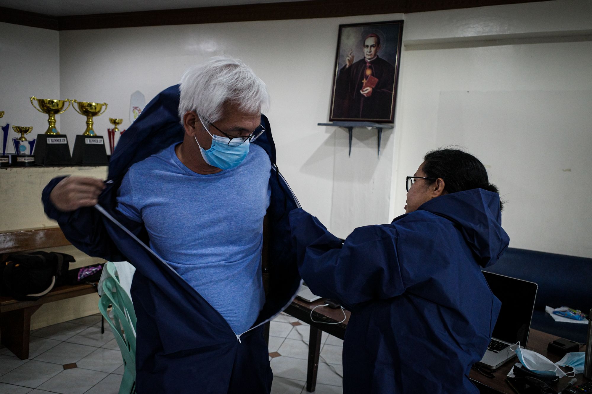 Maria Tan helps Gerard Carreon into a hazmat suit before going into a coverage. (Photo by Mark Saludes)
