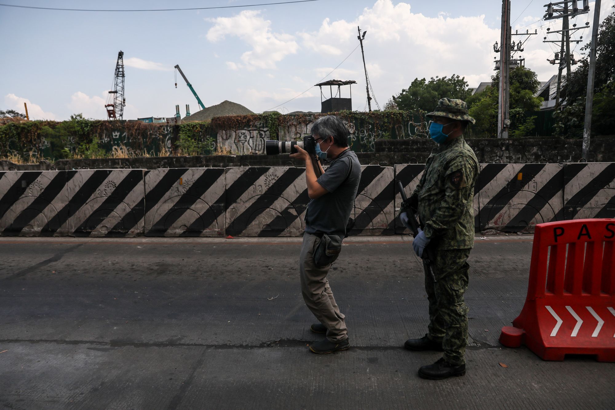 A police officer stands guard as photojournalist Jun Sepe takes pictures during the implementation of the "enhanced community quarantine" in Manila. (Photo by Basilio Sepe)
