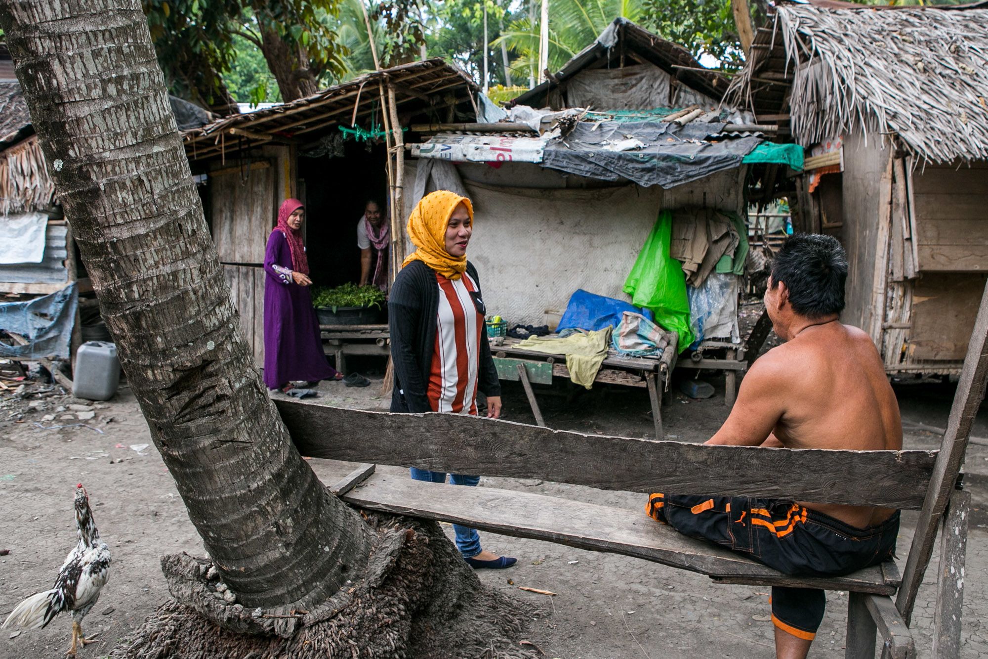 Social worker Noraja Suib of the United Youth of the Philippines-Women, Inc. talks to the father of three young mothers in Maguindanao province.