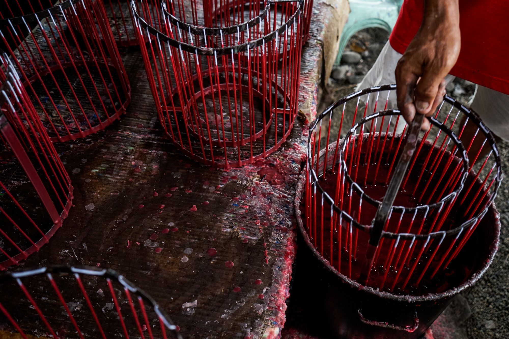 The candle mold with the wicks hanging are dipped into a container of molten wax several times until the desired size of candles is achieved.