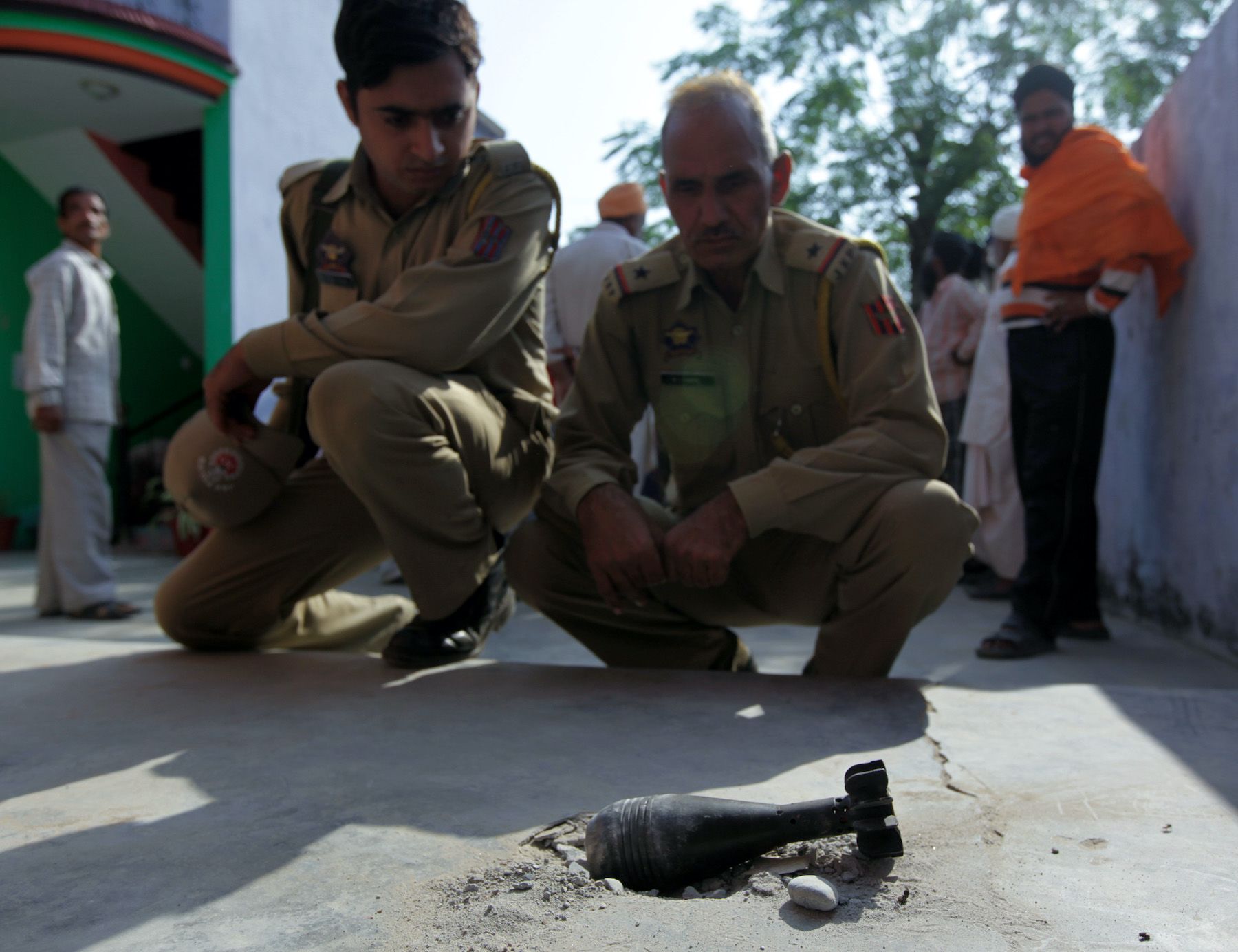 Indian policemen looking at a mortar shell 