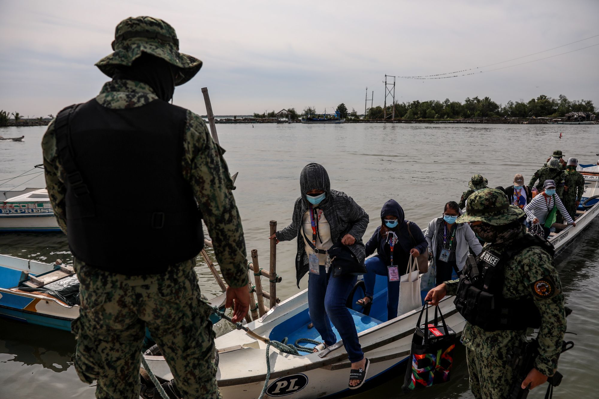 Policemen assist government workers as they alight from a boat in Tibaguin, Philippines
