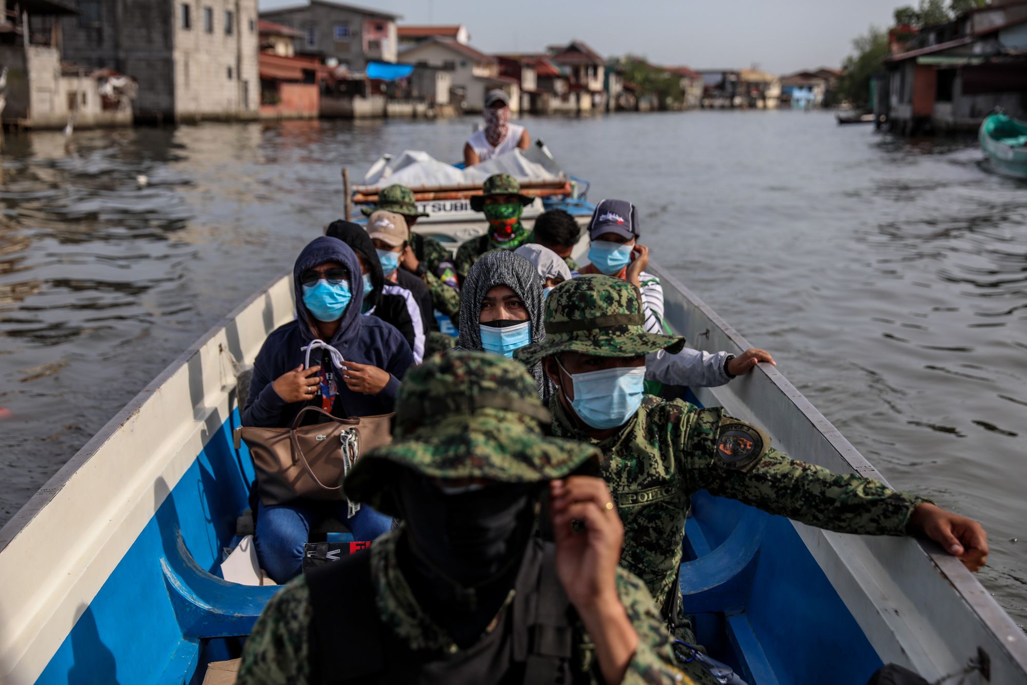 Government workers and policemen ride a boat to the island of Tibaguin, Philippines.