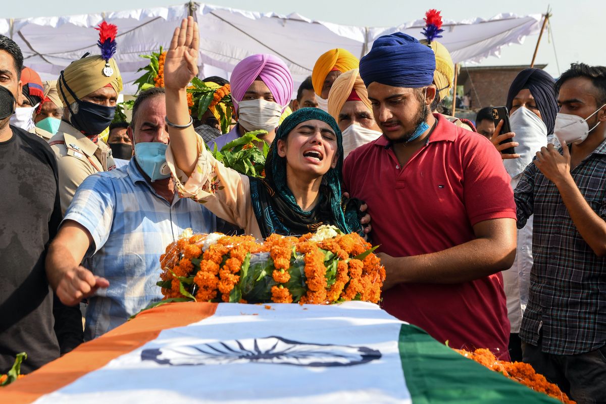 Sandeep Kaur (center) and her brother Prabhjot Singh (right) react after laying the wreaths of flowers on the coffin of their father and soldier Satnam Singh
