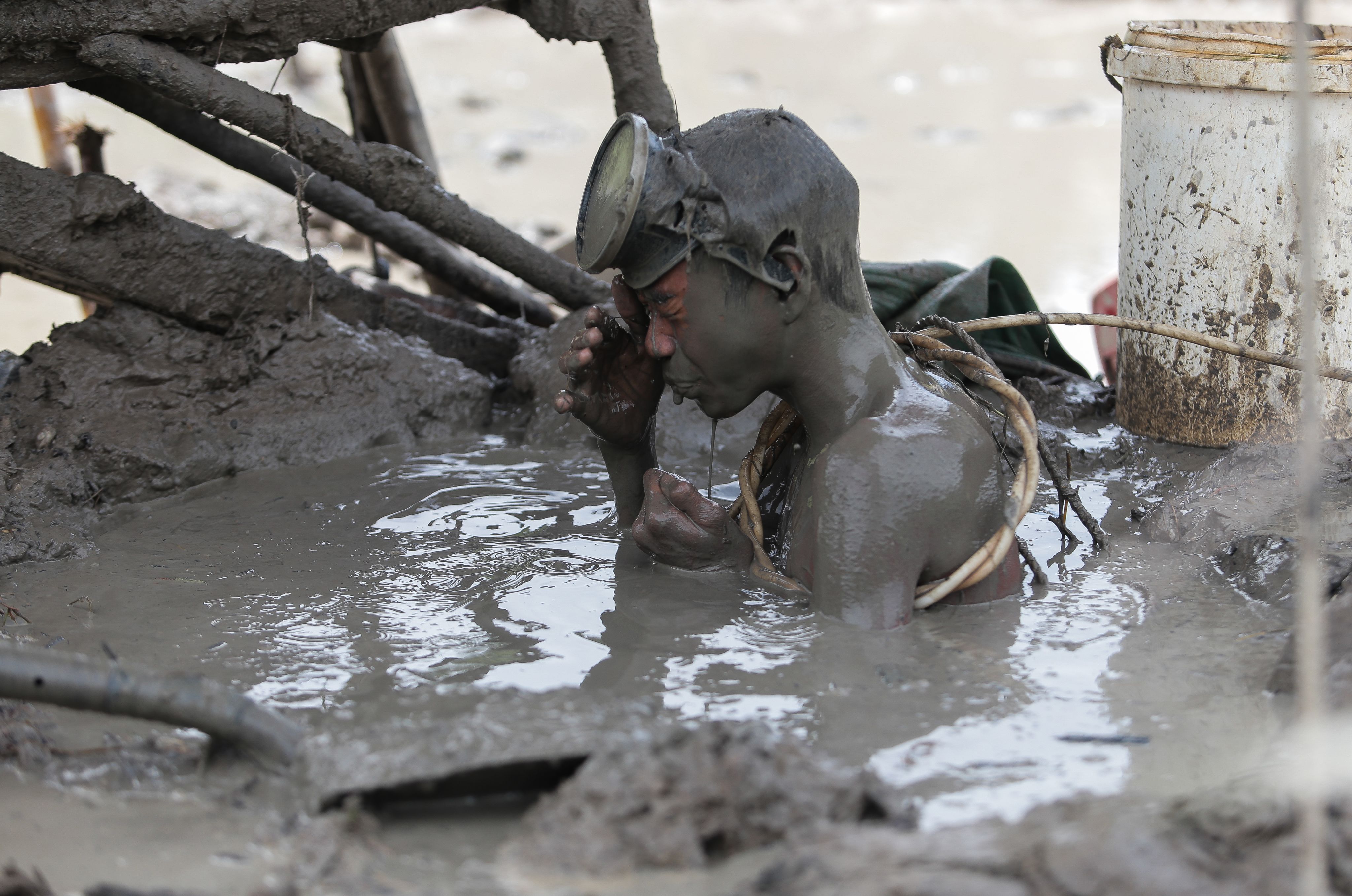 A boy wipes mud from his eyes after compressor diving for an hour straight under 40 feet of mudwater