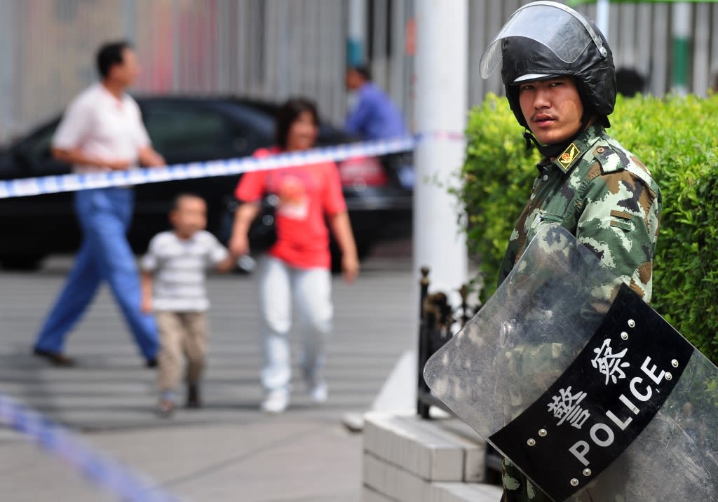 Security personnel in riot gear man their position in front of People's Square while on patrol in Urumqi