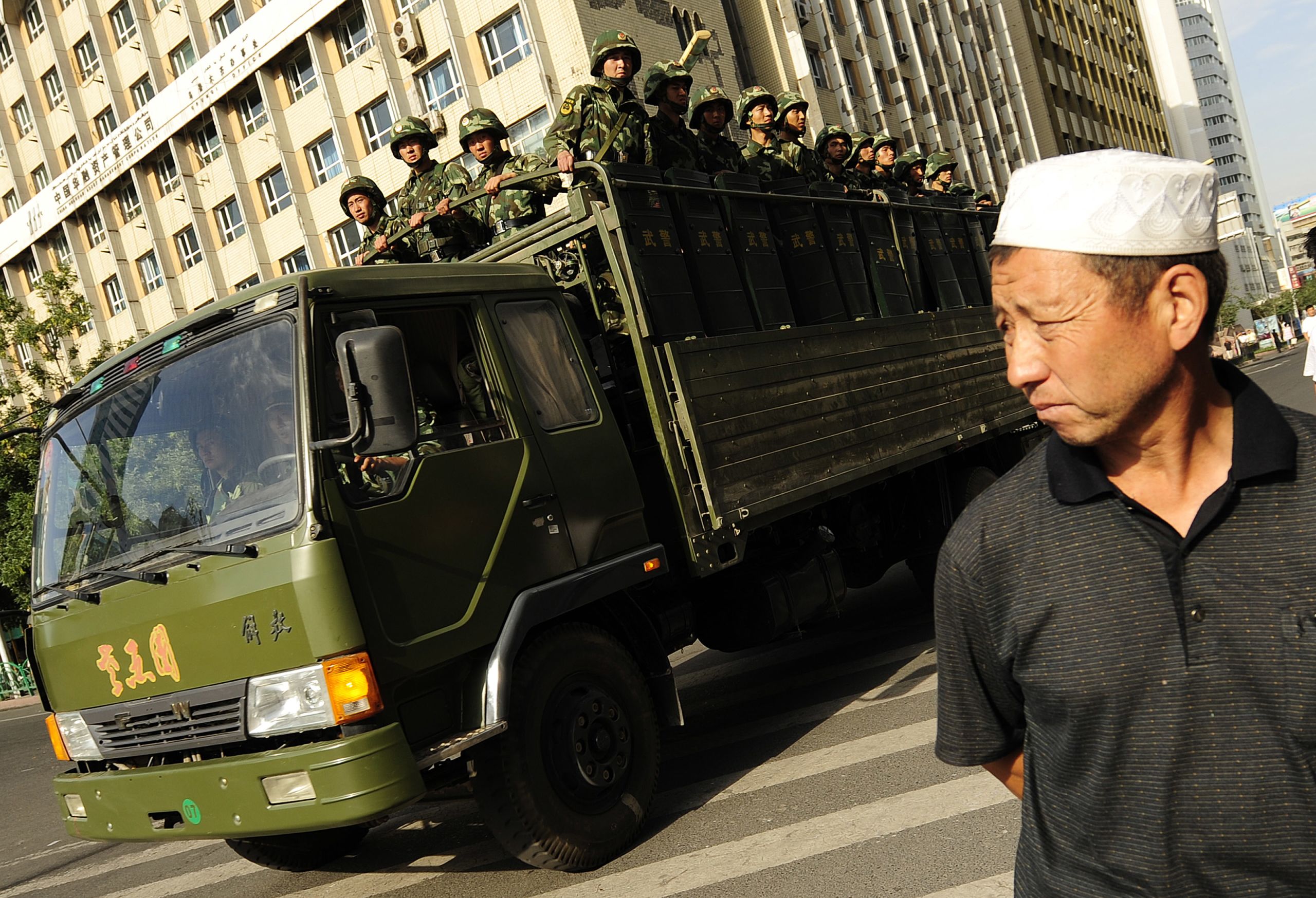 An Ethnic Uygur man watches as an army truck full of Chinese soldiers patrols the street in Urumqi in China's far west Xinjiang province on July 8, 2009. (Photo by Peter Parks/AFP)
